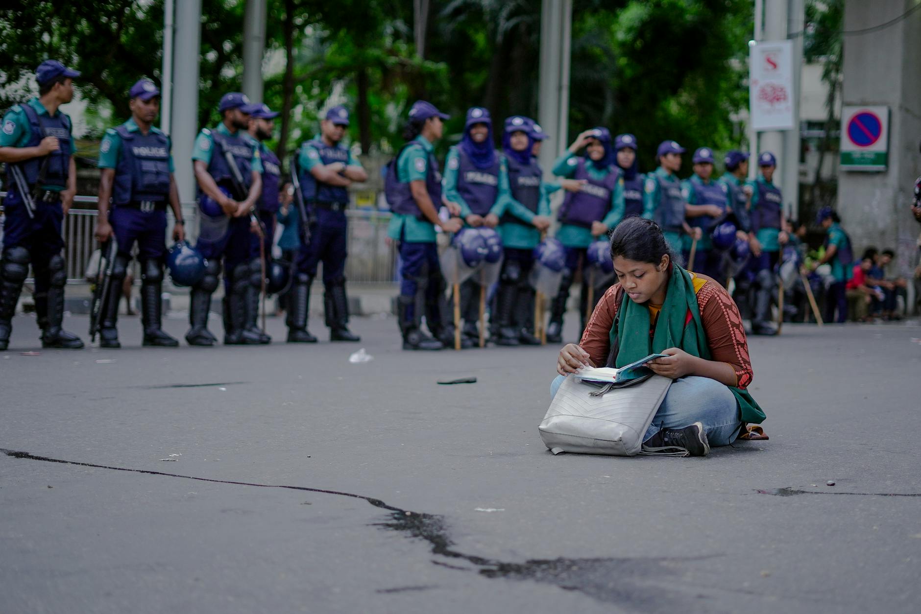 Młoda kobieta czytająca książkę przed kordonem policji podczas protestu