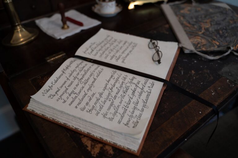 Stary notes z kaligrafią i okulary na drewnianym biurku
